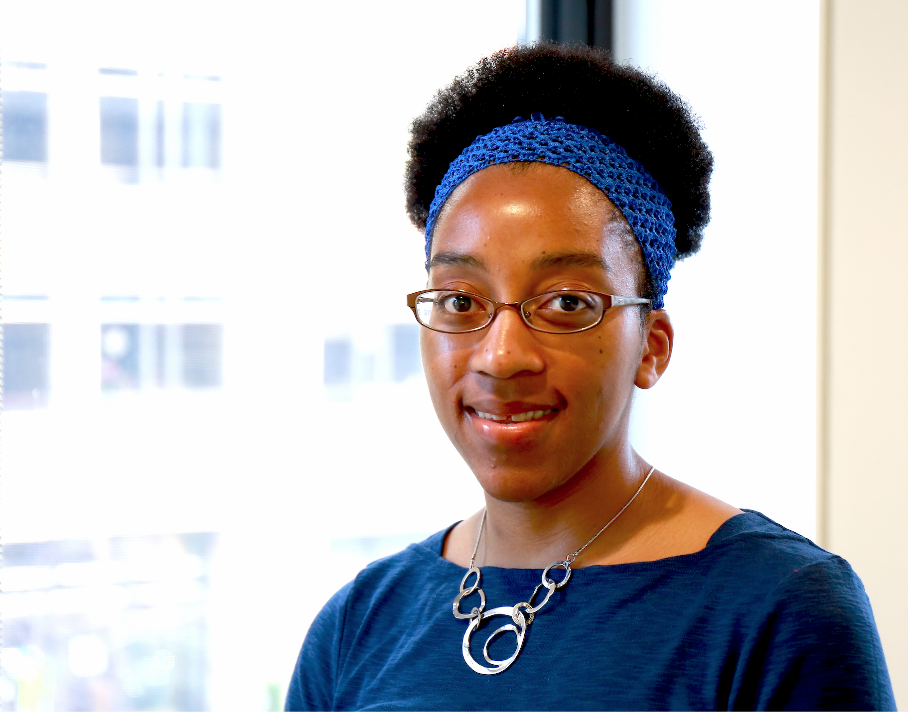 Jasmine Jones headshot with glass background and a blue shirt smiling.