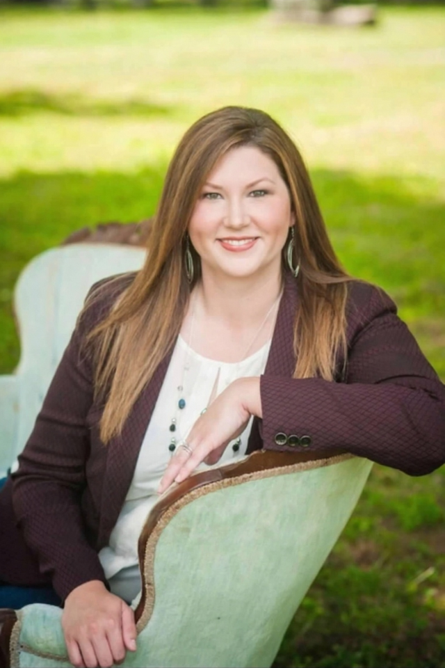 Kyla Pike sitting down on a chair with a green background