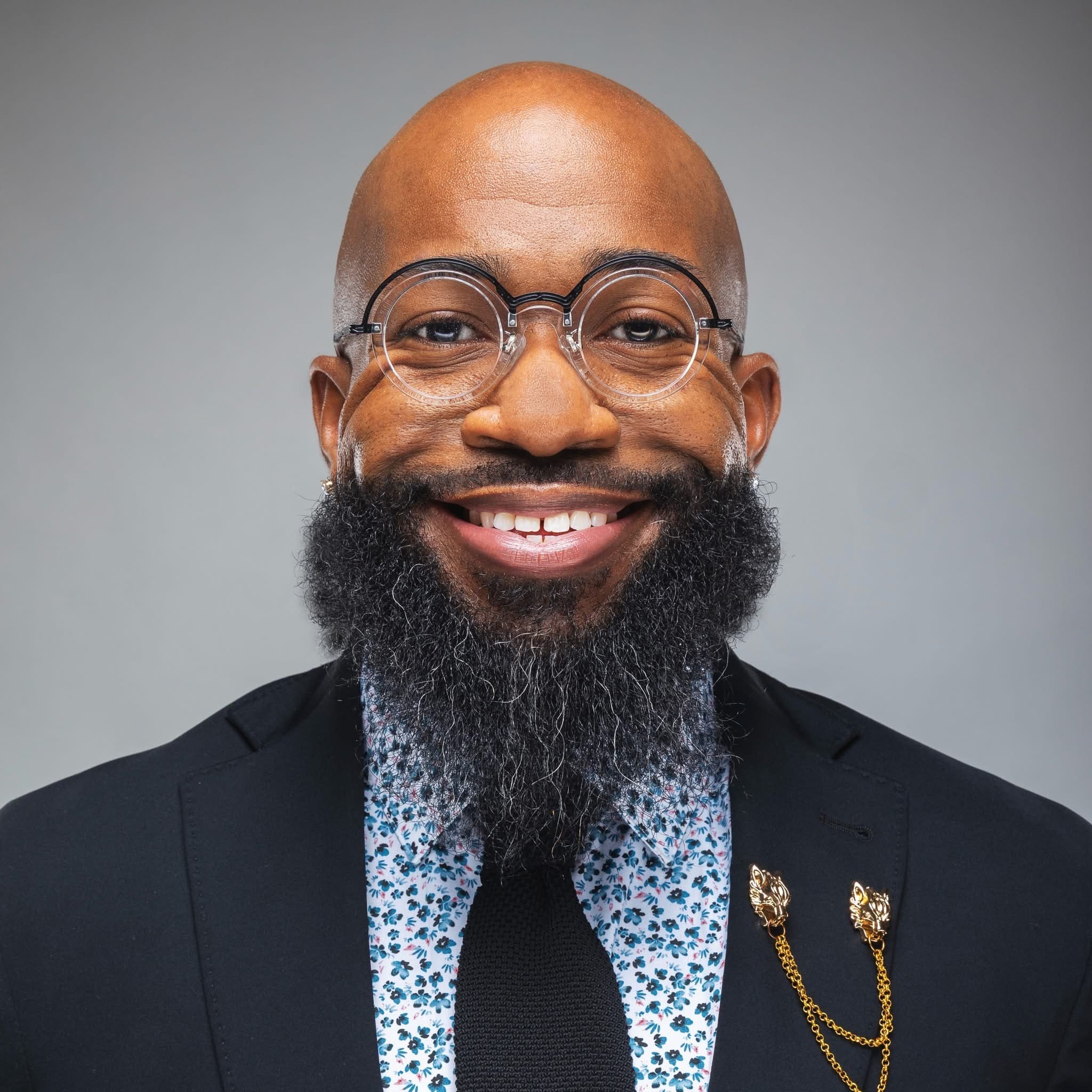 David Simmons headshot wearing a suit with glasses smiling.