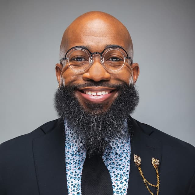 David Simmons headshot wearing a suit with glasses smiling.