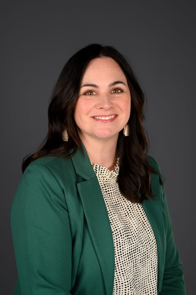 Kristin Dalessio Portrait smiling towards the camera with grey background