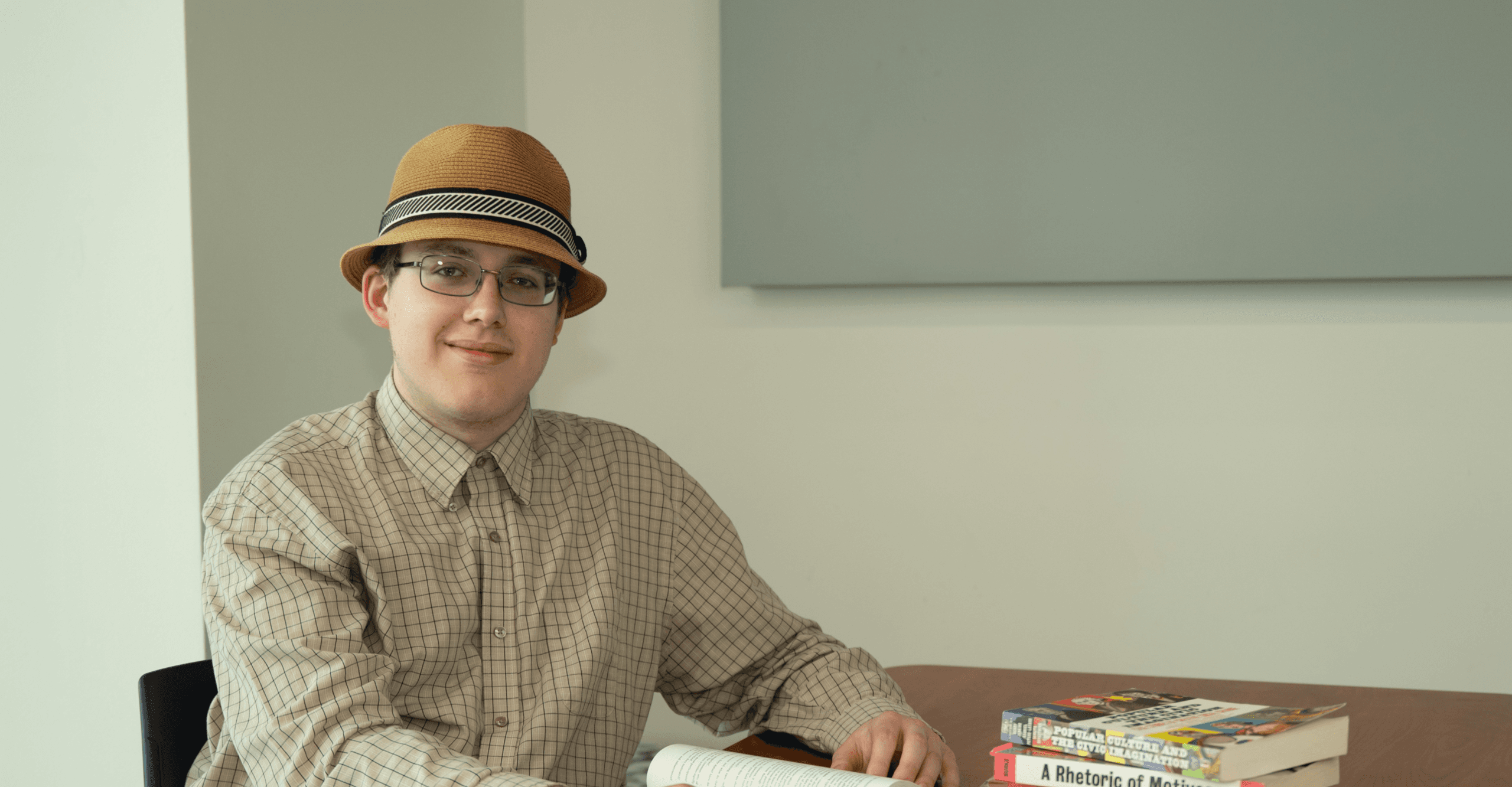 Male student sitting with an open book at a table