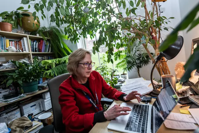 Photo of Dr. Dawn Anderson typing on her computer in her plant-decorated office