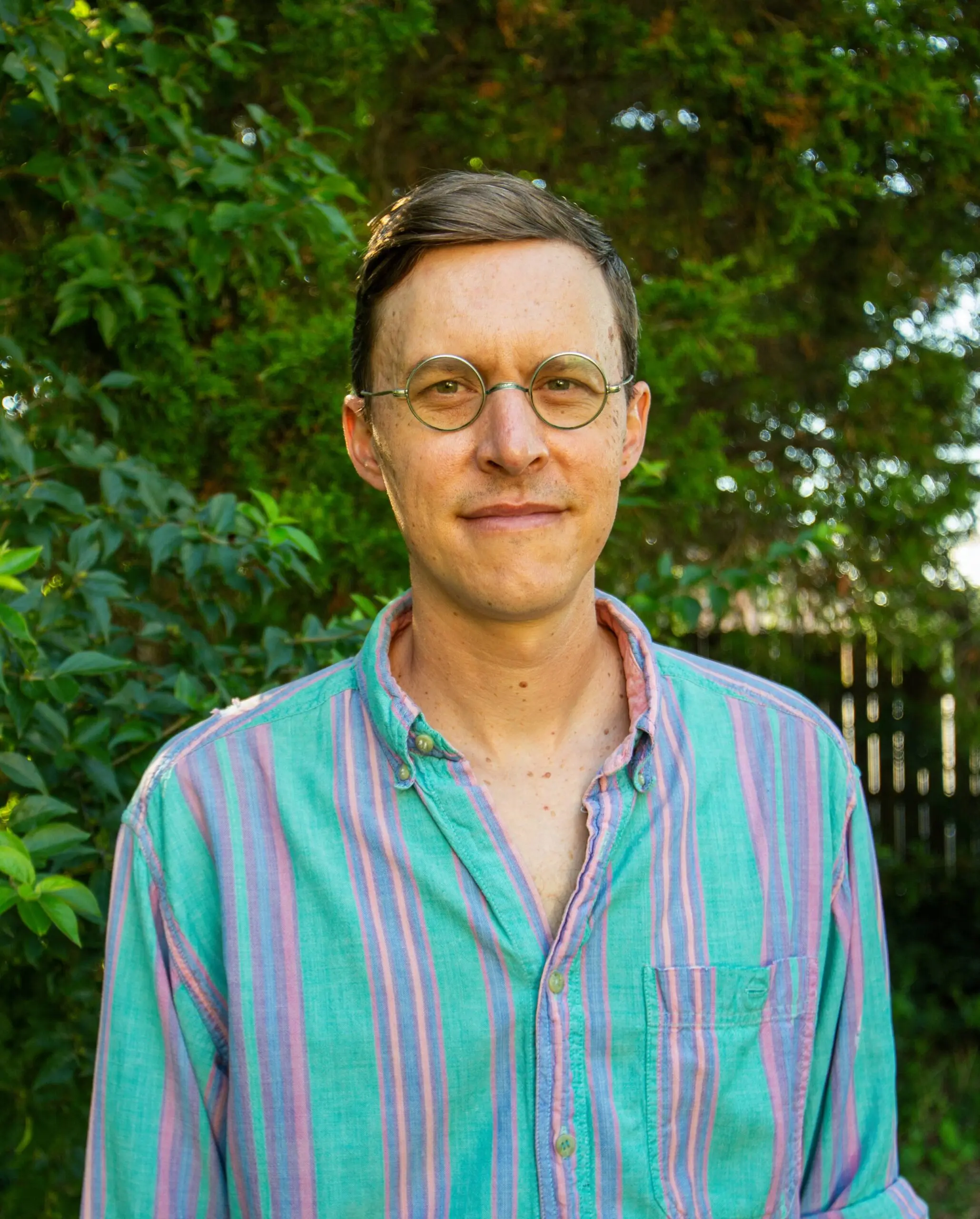 Jesse Montgomery headshot wearing striped vertical shirt with green background