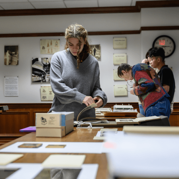 Three students view documents retrieved from the Archives in Hutchins Library.