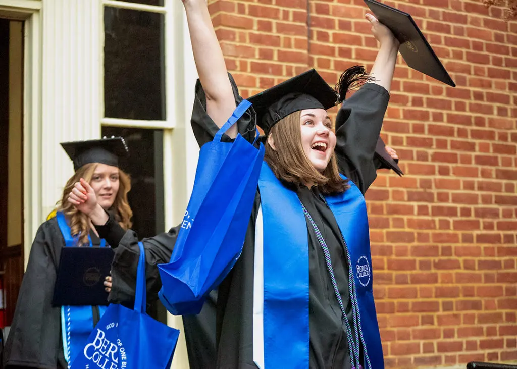 A student celebrating at graduation in their cap and gown.